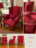 Vintage wingback armchair in red patterned fabric with plaid accent cushion, classic timeless comfort